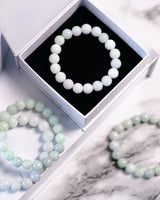 Large white beaded jade bracelets in a white box on a marble surface