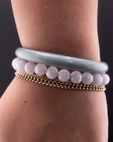Bracelets on a wrist including a white beaded jade bracelet, and a light blue water jade bangle.