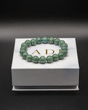 Green beaded bracelet on a white box with 'JADE' branding.